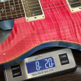Red electric guitar on a digital scale displaying weight