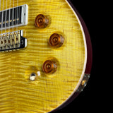 Close-up of a yellow electric guitar with a black pickguard on a black background