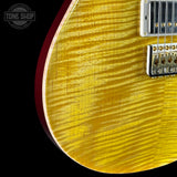 Close-up of a yellow electric guitar with a visible brand logo in the corner.