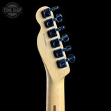 Close-up of the headstock of an electric guitar with a natural maple wood finish and dark blue tuning pegs, shown against a solid black background.