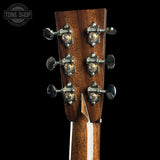 Close-up of a guitar headstock with tuning pegs on a black background, featuring the Tone Shop logo.