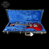 Red electric guitar in a blue-lined case with 'Tone Shop' branding.