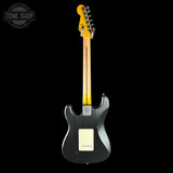 A Fender electric guitar shown from the back against a solid black background, featuring a dark gray/black body, a natural maple neck, and a yellow headstock.