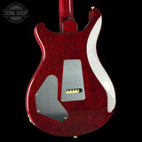 Close-up of a red electric guitar with a visible brand logo in the corner.