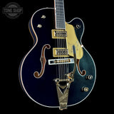 Blue electric guitar with gold hardware on a black background, featuring the Tone Shop logo.