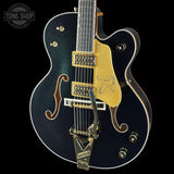 Electric guitar with gold hardware on a black background, featuring 'Tone Shop' logo.