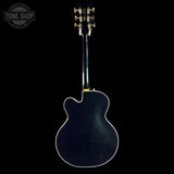 Back view of a blue electric guitar on a black background with 'Tone Shop' logo.