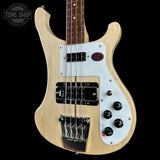 Electric bass guitar with a white pickguard and black hardware on a black background, featuring the Tone Shop logo.