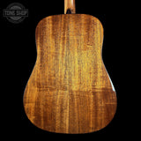 Close-up of a wooden acoustic guitar back with 'Tone Shop' logo.