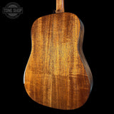 Back view of a wooden acoustic guitar with 'Tone Shop' logo.