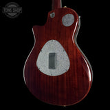 Back view of a electric guitar with a wooden finish and silver pickguard on a black background.