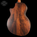 Close-up of a wooden guitar body with 'Tone Shop' logo in the corner.