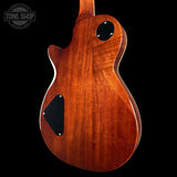 Back view of a wooden electric guitar with 'Tone Shop' logo in the corner.