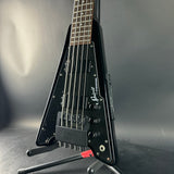 Black electric guitar on a stand against a gray background