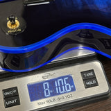 A close-up of a digital scale displaying 8.105 lbs, with a glossy black and blue instrument body resting on the scale platform.