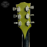 Close-up of the headstock of a vintage electric guitar, showing a lime green backplate with six silver tuning pegs and a black neck, set against a solid black background.