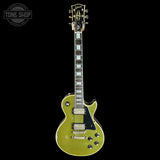 A gold-flecked green Gibson Les Paul Custom electric guitar with a black pickguard and chrome hardware, shown against a solid black background with a Tone Shop watermark in the top-left corner.