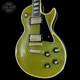 A classic electric guitar with a distressed olive green finish, featuring a black pickguard, chrome hardware, and black control knobs, shown against a solid black background.