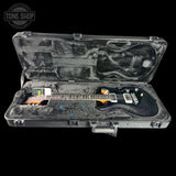 Electric guitar in an open hard-shell case with 'Tone Shop' logo.