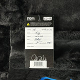 Close-up of a guitar label with text and signatures on a textured black background
