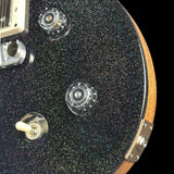 Close-up of a guitar's control knobs and switch on a black glittery surface.