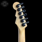 Close-up of the headstock of a Fender electric guitar, showing the natural maple wood neck and six black tuning pegs, set against a solid black background with a Tone Shop watermark in the top left corner.
