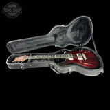 Guitar in a hard-shell case with 'Tone Shop' logo in the corner.