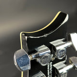 Close-up of a guitar bridge with PRS branding on a blurred background