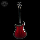 Red electric guitar with a black background, featuring the Tone Shop logo.