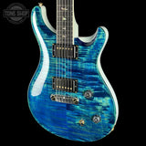 Blue electric guitar with a black pickguard on a black background, featuring the Tone Shop logo.