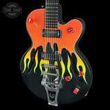 A custom electric guitar with a black and orange body, featuring yellow and black flame decals, red dice graphics, and a silver tremolo system, shown against a solid black background.