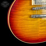 Close-up of a guitar with a sunburst finish on a black background, featuring the Tone Shop logo.