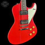 Red electric guitar with a white pickguard on a black background, featuring the Tone Shop logo.