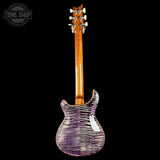 Guitar with a purple flame maple body on a black background, featuring the Tone Shop logo.