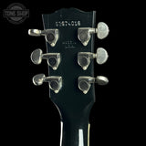 Close-up of a guitar headstock with tuning pegs on a black background, featuring the Tone Shop logo.