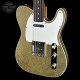 Gold glitter electric guitar with a white pickguard on a black background, featuring 'Tone Shop' branding.