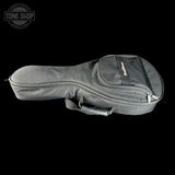 A black acoustic guitar soft case with a front zippered pocket and a small Tone Shop logo, shown against a solid black background.