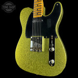 Green glitter electric guitar with a black pickguard on a black background, featuring 'Tone Shop' branding.