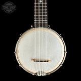 A front-facing close-up of a banjo against a solid black background, featuring a light-colored headstock, silver metal rims, and a dark fretboard. A Tone Shop watermark is visible in the upper left corner.