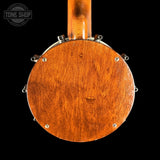 Close-up of the back of a wooden banjo, showing the round soundboard, metal lugs, and neck against a black background. A Tone Shop watermark is visible in the upper left corner.