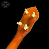Close-up of the headstock of a wooden stringed instrument, likely a ukulele, featuring a warm reddish-brown wood finish and four cream-colored tuning pegs against a solid black background.