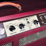 Close-up of a red crocodile-embossed amplifier head with a cream control panel featuring black knobs and white text, including a handle and speaker grille.