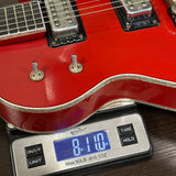 Red electric guitar on a digital scale displaying weight