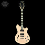 Electric guitar with a beige finish on a black background, featuring the Tone Shop logo.