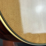 Close-up detail of an acoustic guitar body showing the natural wood grain, a glossy finish, and the edge rosette with black and gold stripes.