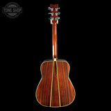 The back of a wooden acoustic guitar with a glossy reddish-brown finish and a gold-toned center stripe, shown against a solid black background with a Tone Shop watermark in the top-left corner.