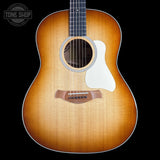 A front-facing acoustic guitar with a natural sunburst finish, featuring a white pickguard and a dark fretboard, shown against a solid black background with a Tone Shop watermark in the top left corner.