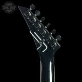 Close-up of a guitar headstock with tuning pegs on a black background, featuring the Tone Shop logo.