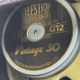 Close-up of a Celestion Vintage 30 G12 loudspeaker driver showing the black and gold label with silver metal rim.