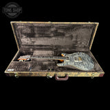 An electric guitar with a blue-gray flamed maple top and orange maple neck, displayed inside an open vintage-style hard case with a dark gray velvet interior. A Tone Shop watermark is visible in the top left corner.